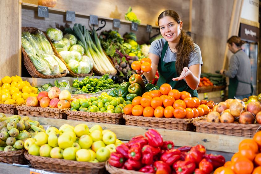 Comerciante sorrindo em uma banca de frutas e verduras